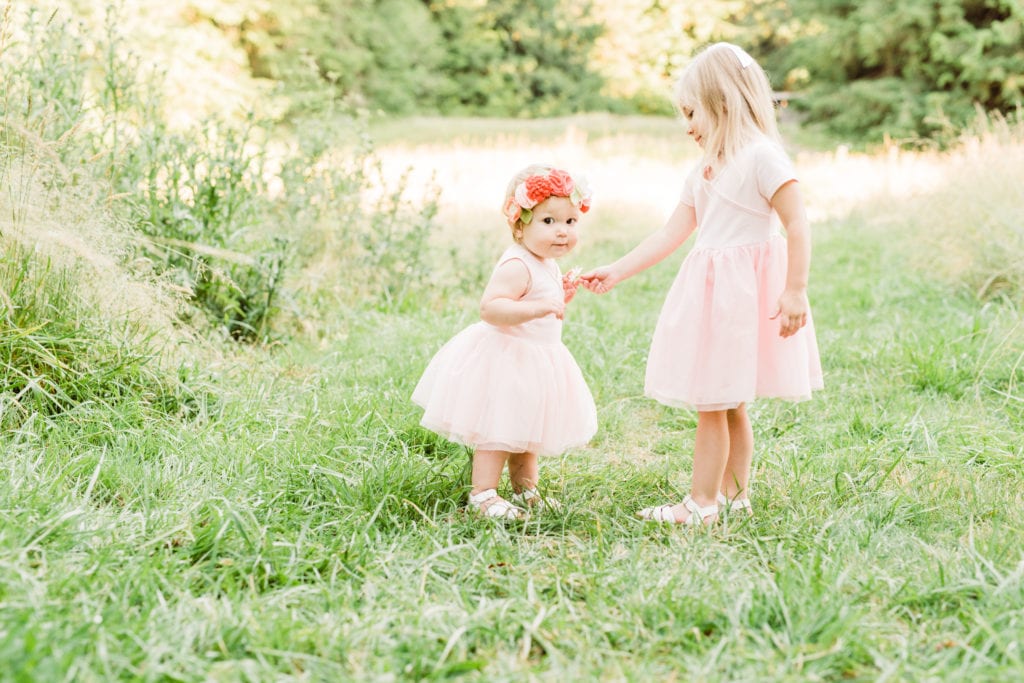 Sister's in their matching pink tulle dresses at a golden hour outdoor photo shoot. 