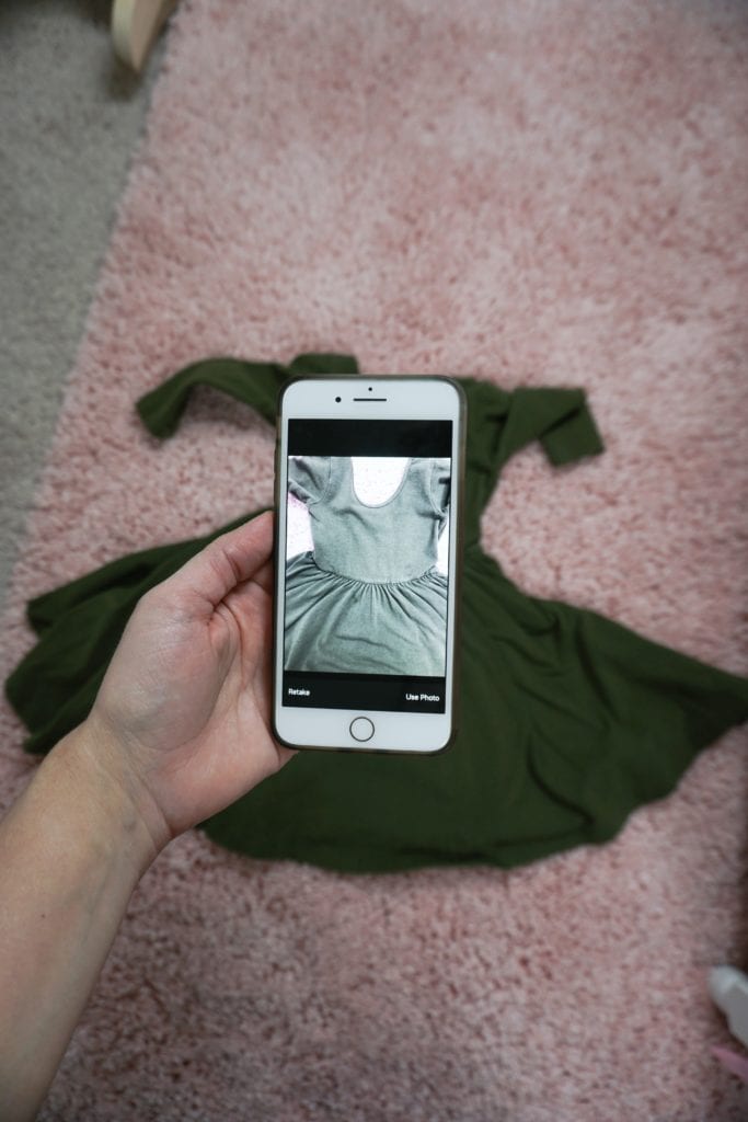 hand holding cell phone taking photo of dress to sell on the Kidizen app