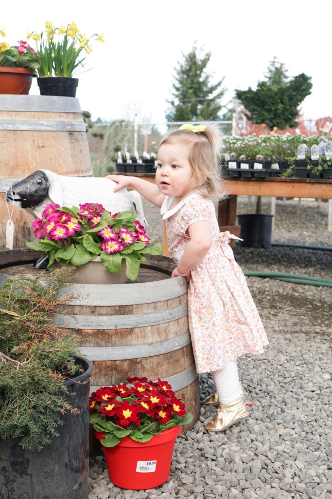 Baby girl in a spring smocked floral dress at a garden center 