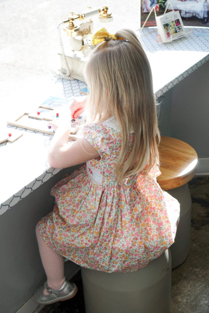 Toddler girl in a floral smocked spring dress at a cupcake shop