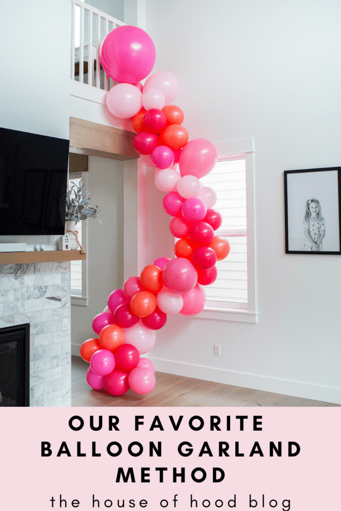 Pink balloon garland hanging off stair railing 