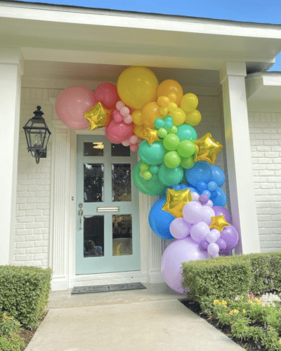 Rainbow balloon garland on front porch 