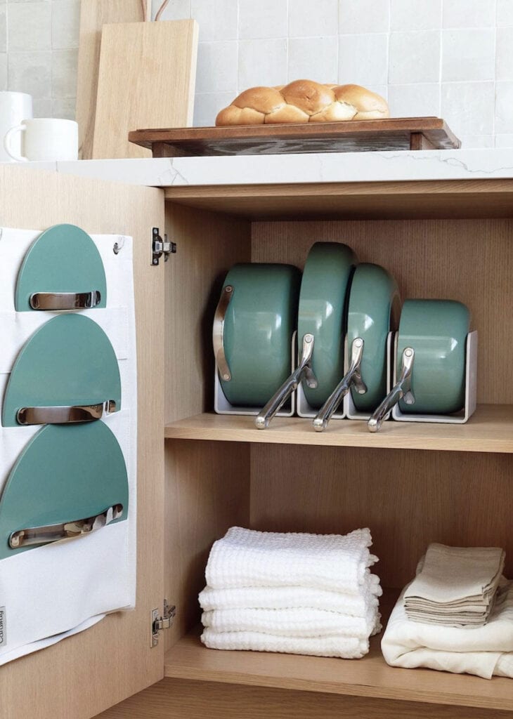 Caraway Cookware in green in a kitchen cupboard